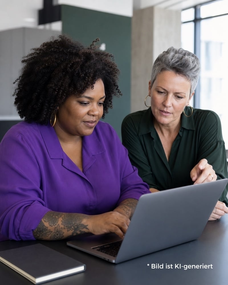 KI-generierte Darstellung von zwei Marketingexpertinnen arbeiten im KI-Mentoring gemeinsam an einem Laptop.